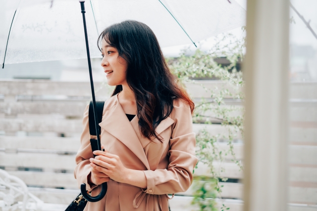 雨の中傘をさして歩いている女性の画像