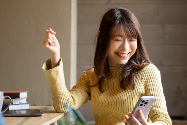 スマホを見て喜んでいる表情の女性の画像