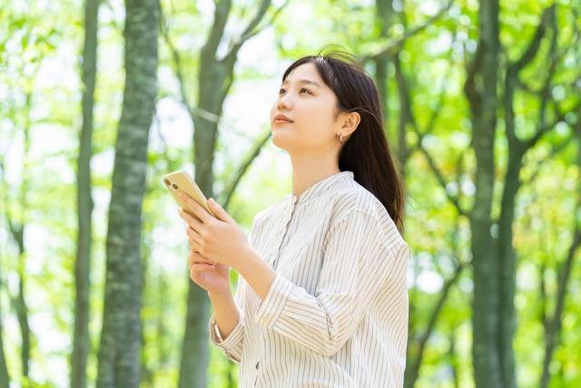 スマホを手に斜め上を見つめる女性