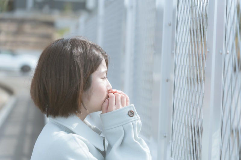 フェンスから何かを見つめている女性の横顔の画像