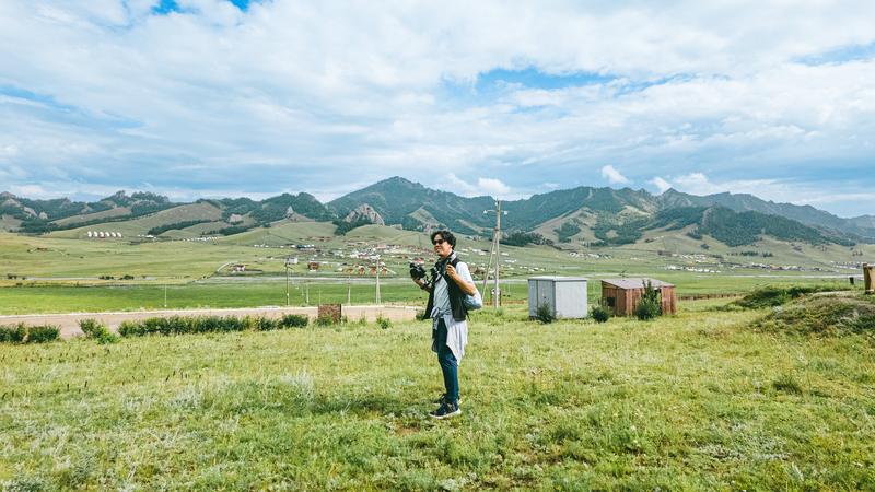 広大な草原で撮影をしている男性の画像