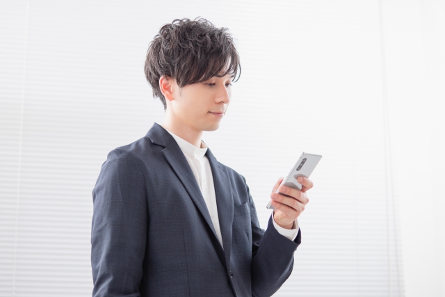 スマホを見ている男性の画像