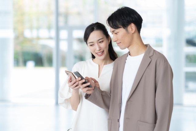 スマホを見るカップルの画像