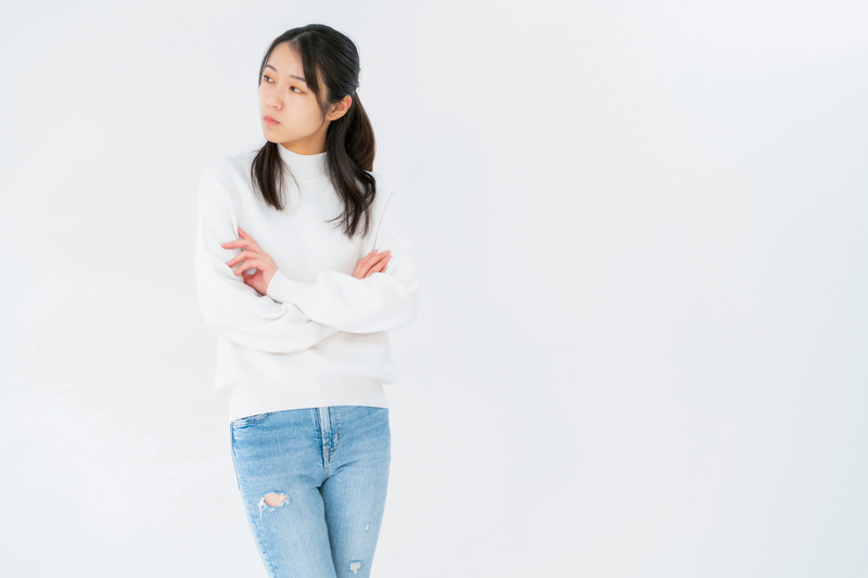 不服そうな表情で立つ女性