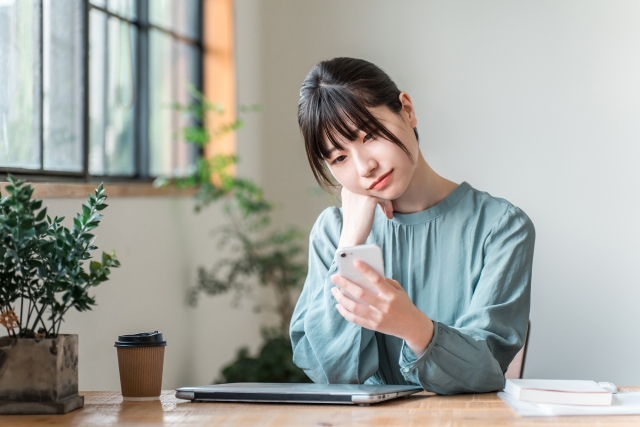 スマホを見ながら考える表情をしている女性
