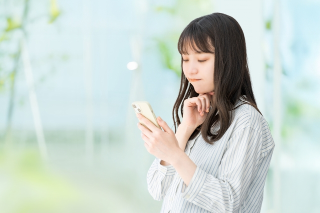 屋外でスマホをそうさしている女性