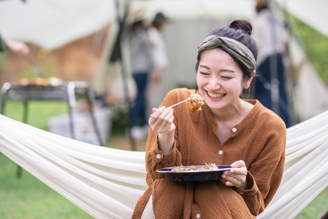 ハンモックに座り食べ物を美味しそうに食べる女性