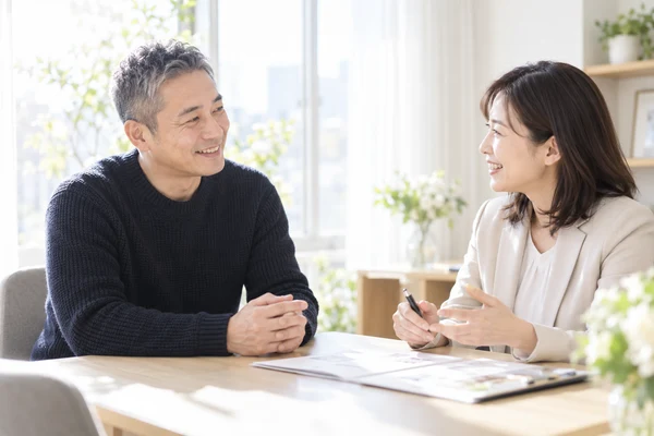 明るい相談室で、担当のアドバイザーの話を聞いている40代後半の男性