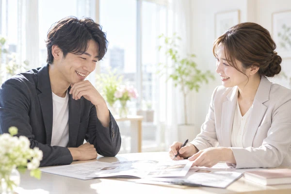 明るい相談室で女性の担当者の話を聞いている20代の男性