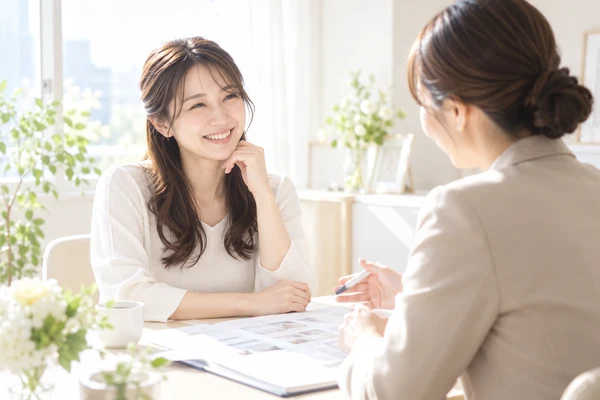 明るい相談室で、担当のアドバイザーに婚活の計画を相談している30代の女性