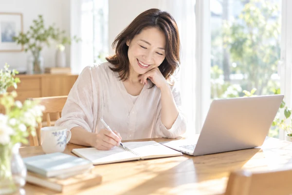 自宅のテーブルで、婚活の方法を書き出して見比べている40代の女性
