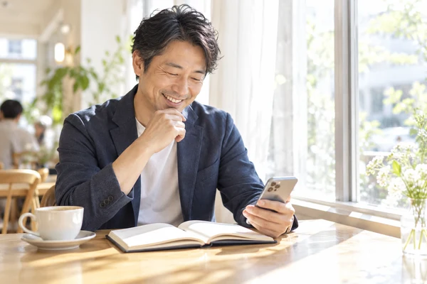 カフェの窓際で、婚活にかかる料金を見比べている40代の男性