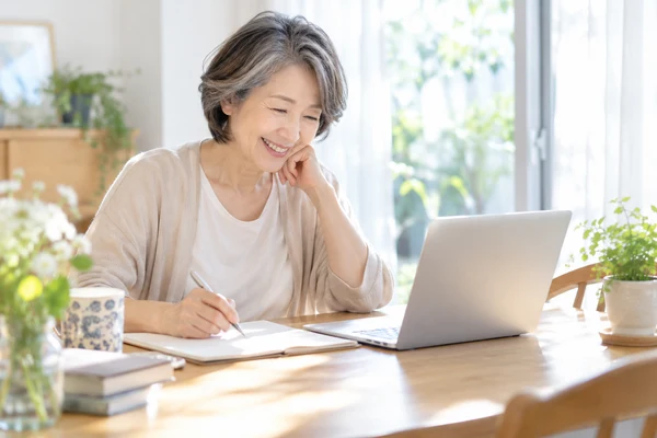 自宅のテーブルで、婚活の方法を書き出して見比べている50代の女性