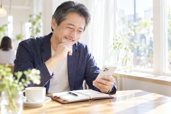 カフェの窓際で、婚活にかかる料金を見比べている50代の男性
