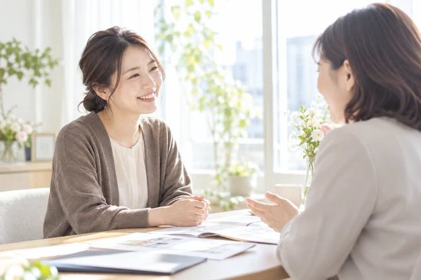 明るい相談室で、担当のアドバイザーの話を聞いている30代前半の女性