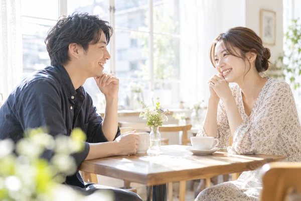 明るい窓辺のカフェで、向かい合って話している30代の男女