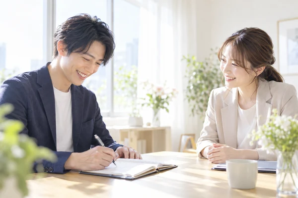 明るい相談室で、担当のアドバイザーと今月の活動の計画を立てている30代の男性