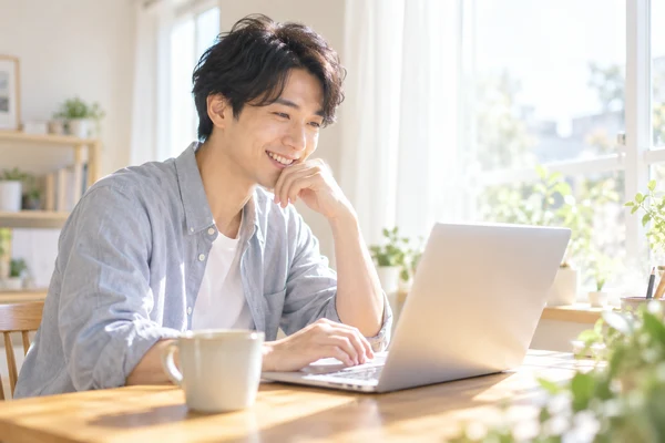 自宅の窓辺の机で、お相手のプロフィールを見て申し込む相手を選んでいる30代の男性